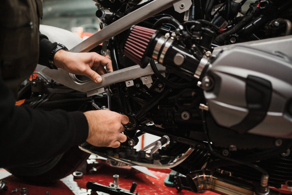 Repairman repair motorcycle, maintenance in garage. Mechanic fixing bike in a modern shop